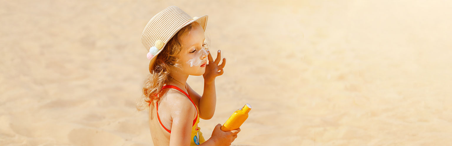 Child apply sunscreen on the beach